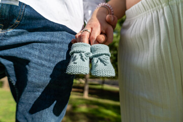 Future parents holding baby booties announcing pregnancy news