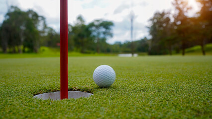 Golf ball is on a green lawn in a beautiful golf course with morning sunshine.