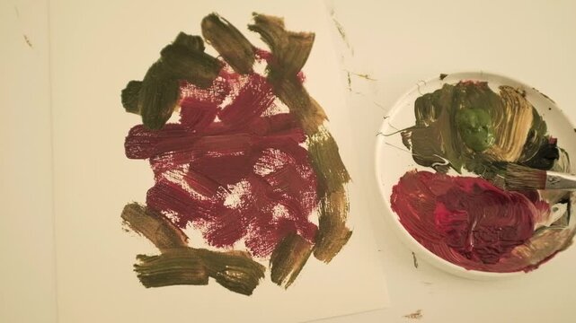 Closeup slow motion video of an abstract acrylic or oil painting in pastel pink and green colors. Creative process of an artist painting on canvas. State of flow and creativity.