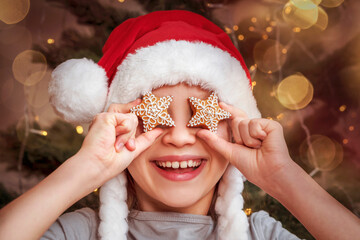 Christmas Gingerbread Cookies in front of Christmas Child Eyes. Happy Little Kid in Santa hat with...