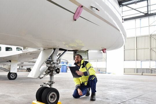 Aircraft mechanic inspects and checks the technology of a jet in a hangar at the airport