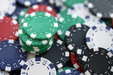 Close up of a group of casino chips on a green mat for poker or dice games indoors