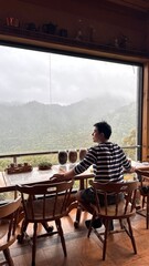 Handsome Man Relaxing in Cafe with Beautiful Morning Misty Valley View