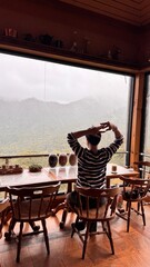 Handsome Man Relaxing in Cafe with Beautiful Morning Misty Valley View