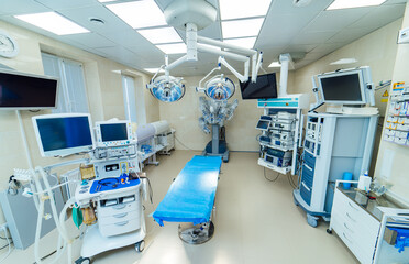 Bright modern operating room with robotic equipment. Bright and clean operating room with robotic surgical equipment, lamps and monitors in hospital.