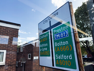 City centre road sign in Manchester displaying routes to Oldham Preston Bolton and Salford.