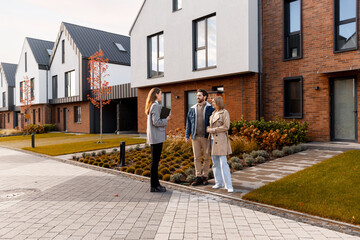 Real estate agent showing new modern townhouses to young couple