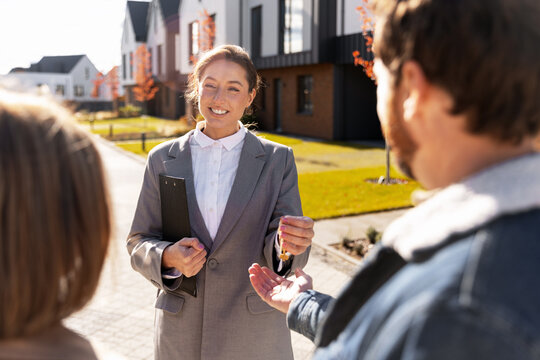 Real estate agent handing keys to home buyer couple