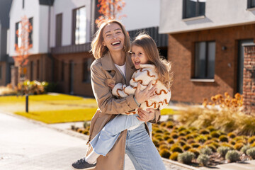 Naklejka premium Mother and daughter laughing, hugging outdoors on sunny autumn day