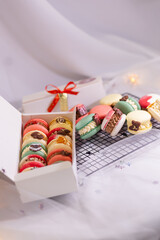 macaron dessert for christmas. homemade unique cookie. bow and sprinkles. various colors. present box. white