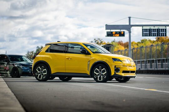 Brno, Czech Republic - October 24, 2025: Yellow electric city car Renault 5 outdoors on a racing circuit. Small battery-powered car made in France.