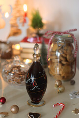 Cookie jar, tea, wine, nuts, books, lit candles and Christmas decorations on the table. Cozy Christmas hygge at home. Selective focus.