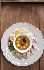 Thai rice noodles with fish ball curry sauce served with boiled eggs, bean sprouts, and fresh vegetables. Authentic Thai traditional dish known as 