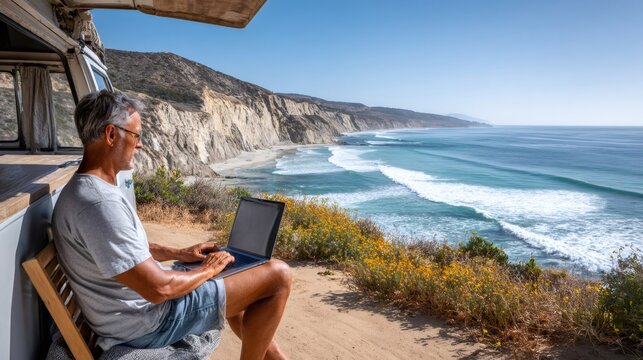 Man working on laptop from camper van at remote beach - Powered by Adobe