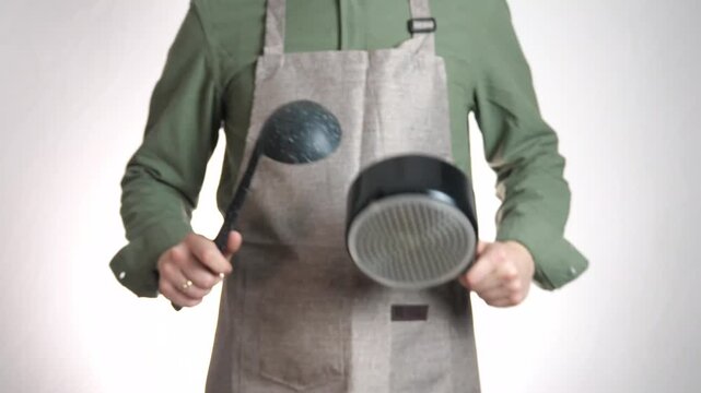 A rhythmic, abstract shot from a professional kitchen. The action of a ladle striking a pot signifies preparation, activity, and the beginning of a cooking process. 