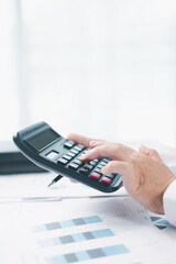 Close up of businesswoman using calculator for financial analysis and accounting on office desk...