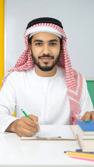 Arab Man Writing at Desk with Traditional Headdress.