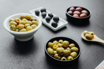 Close view of assorted olive types served in white dish on dark background