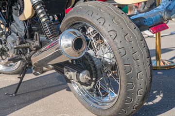 Close-up of a turned motorcycle wheel, with treaded tire and visible spokes and brake disc, against a subdued background suggesting an outdoor setting