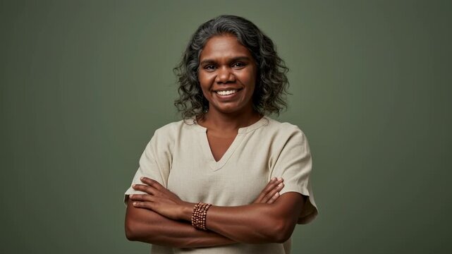 Smiling woman with crossed arm gray hair middle age smile crossed arm neutral top beaded bracelet studio portrait warm confident empowering expression