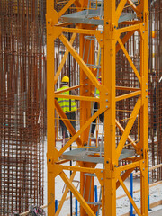 Fototapeta premium Construction Workers Among Reinforcement Bars and Heavy Equipment