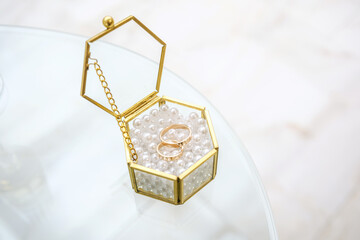 Wedding rings in golden box with pearls for love and marriage celebration concept