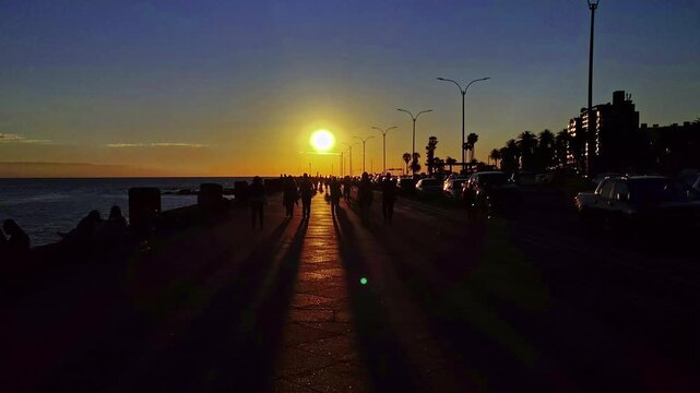 Large group of people walking at rambla de montevideo at sunset springtime day, barrio palermo neighborhood, uruguay