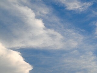 A bluish sky background with a pattern of soft white clouds. Full frame of a soft cloudy sky. Beautiful abstract blue sky and wispy clouds.