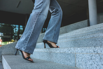 Woman in jeans and heels walking up outdoor stairs