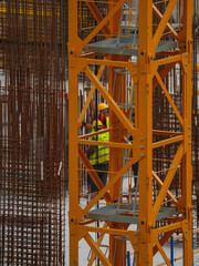 Construction Workers Among Reinforcement Bars and Heavy Equipment
