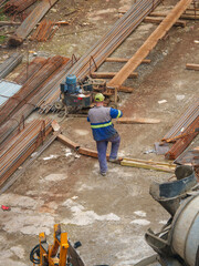 Construction Workers Among Reinforcement Bars and Heavy Equipment
