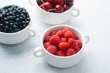 Bowls of raspberries, blueberries and cherries for fruit trio, diet or nutrition concept