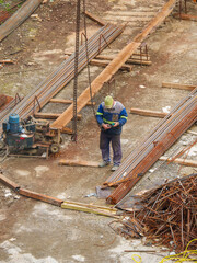 Construction Workers Among Reinforcement Bars and Heavy Equipment