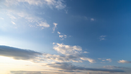Blue sky with scattered white clouds under the sunlight