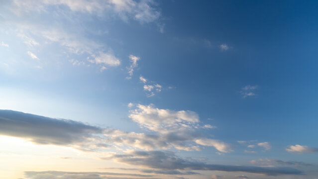 Blue sky with scattered white clouds under the sunlight