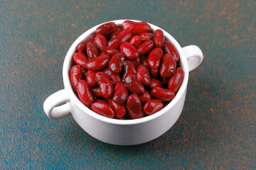 Red kidney beans in white bowl on dark background for protein, vegan food or healthy eating concept