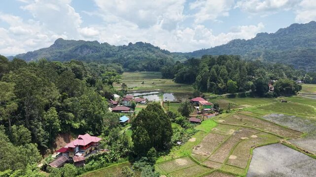 Aerial view of rice terraces near Rantepao, Tana Toraja, Indonesia, with lush greenery, water-filled paddies, and scattered rocks.	