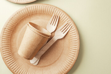 Sustainable tableware with eco paper cups and forks on green background minimalist concept