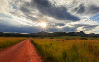 Dramatic African landscape of Swaziland glowing under golden sunset sky with rolling hills