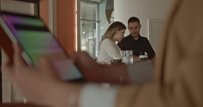 Two dedicated business partners are actively collaborating on their small business project in a vibrant, modern cafe.