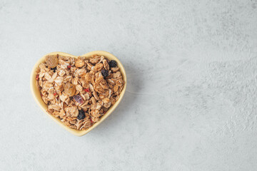 Heart shaped bowl with granola mix on light background