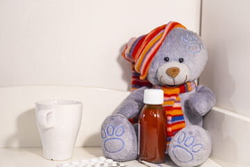 Seasonal flu concept for kids. Toy plush teddy bear with medical drugs and pills, medicines, thermometer.