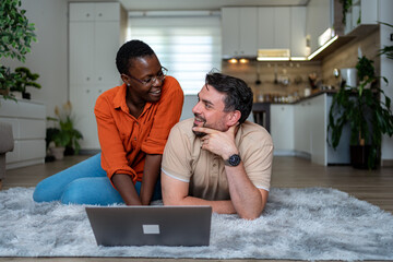 Couple enjoying a casual moment together at home while working on a laptop