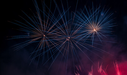 Spectacular Fireworks Explode in Night Sky with Blue and Red Trails Over City Celebration