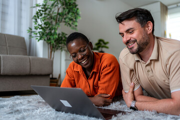 Couple enjoys shared moment while using laptop on cozy living room floor in bright afternoon light