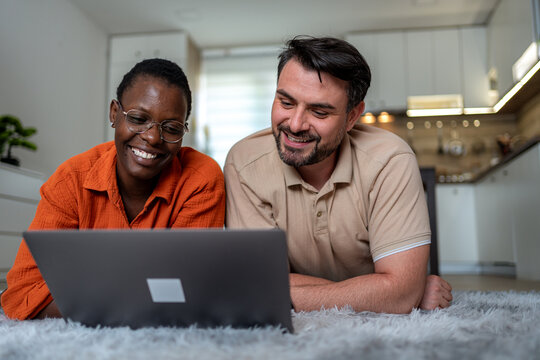 Couple enjoying time together while using a laptop in a cozy home setting