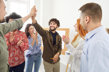 Multinational group of positive business people high fiving each other in an modern office....