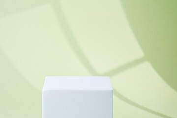 Minimal single cube pedestal displayed on pastel green background