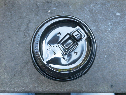 A top-down view of a takeaway coffee cup lid placed on a stone surface, highlighting minimalist detail, texture, and everyday urban lifestyle moments.