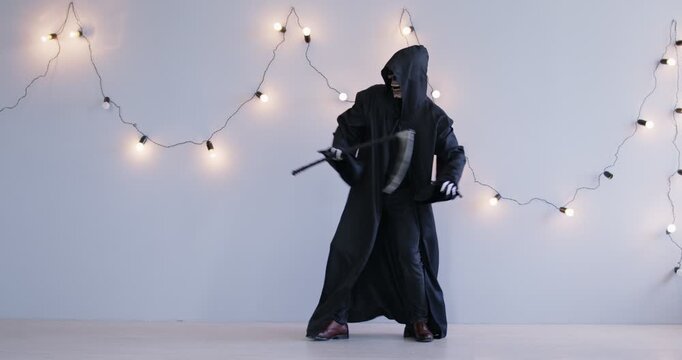 Halloween Grim Reaper funny scythe dance, cosplay black costume, Angel of Death scary in black hooded cape, skull face mask, skeleton glove for theme party spooky gothic ball event, holiday atmosphere